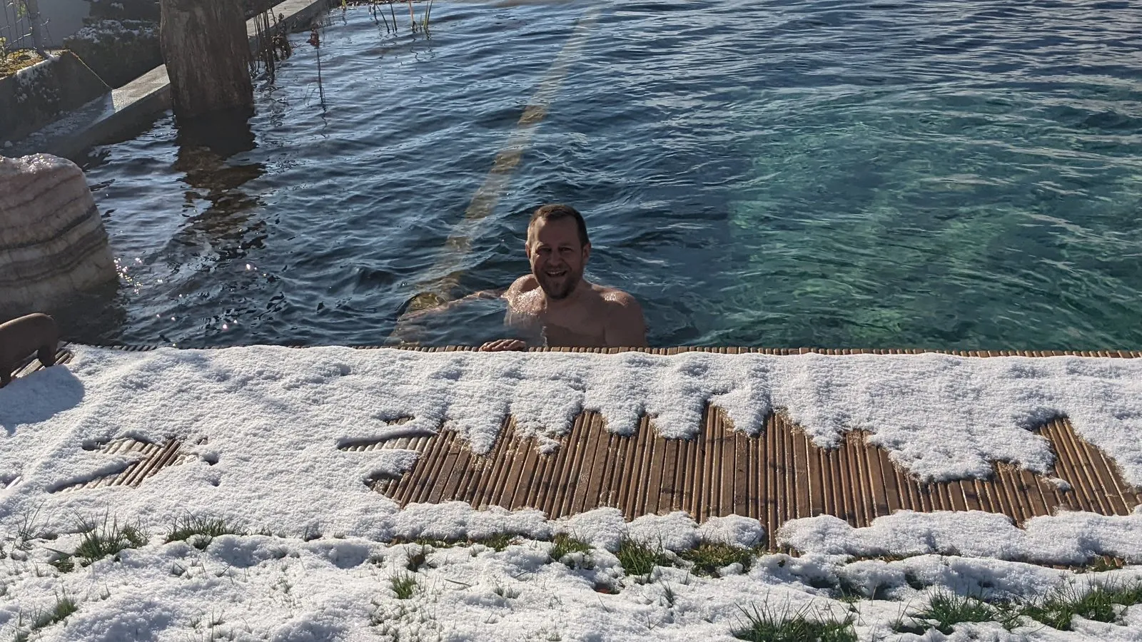 Im verschneiten Garten im kalten Wasser, lachend am Beckenrand